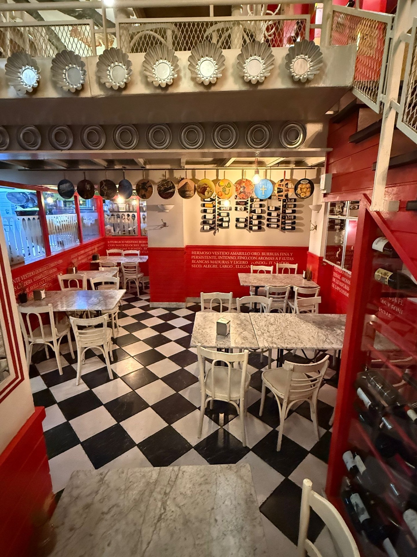 Primera planta del restaurante con suelo de damero blanco y negro, paredes rojas y bodega